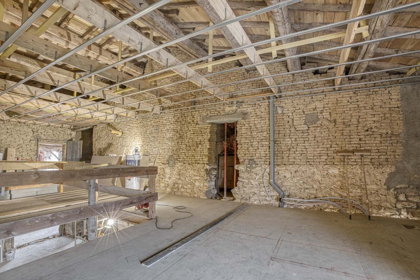Intérieur d'une maison en pierres avec une armature en métal pour faux plafond
