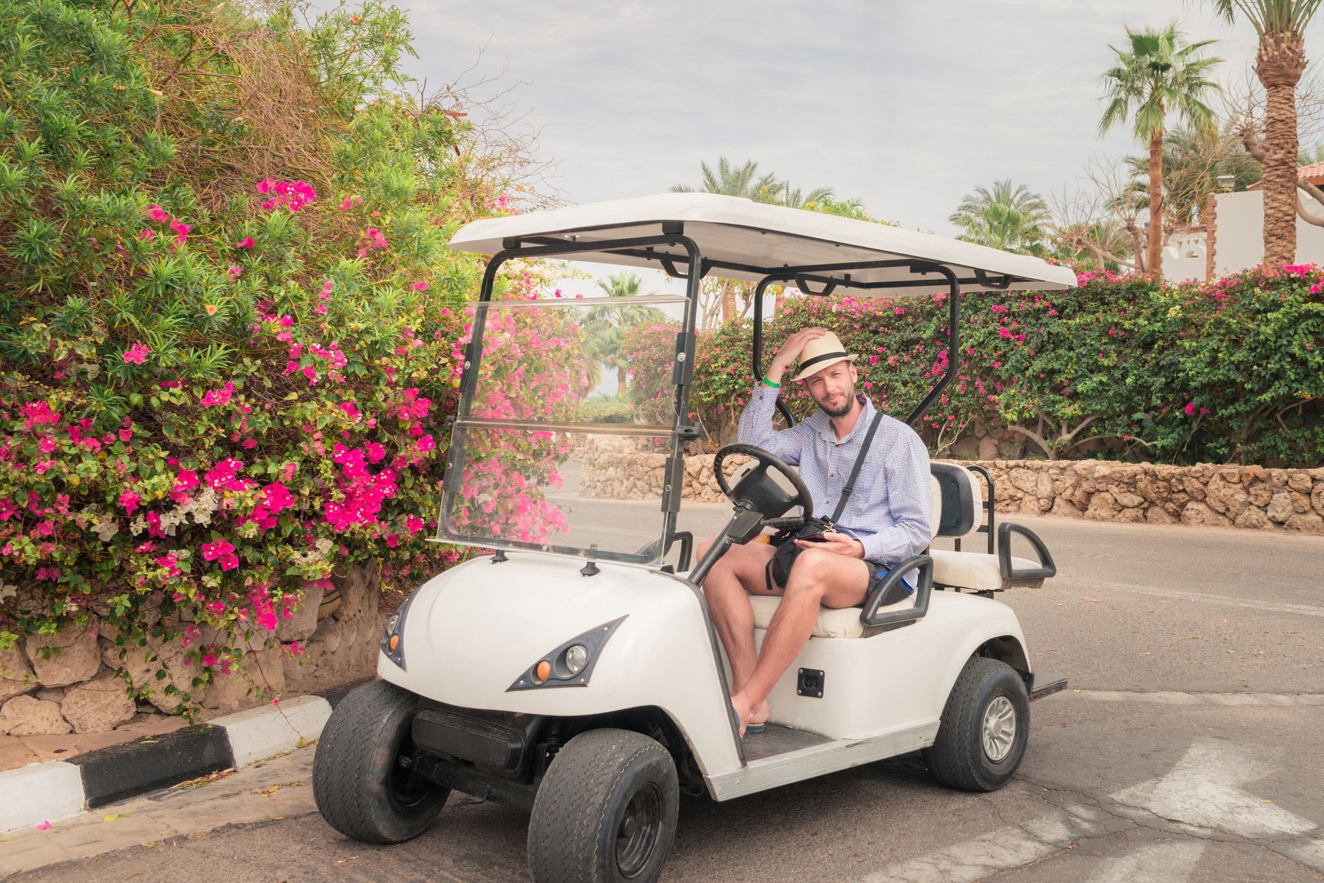 Touriste avec chapeau dans une golfette.