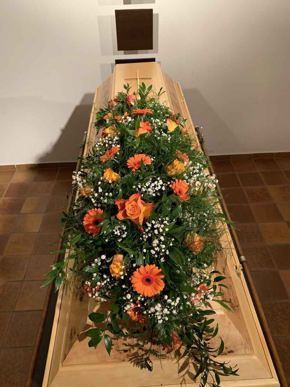 Sarg mit Blumenschmuck in Orange und Weiß