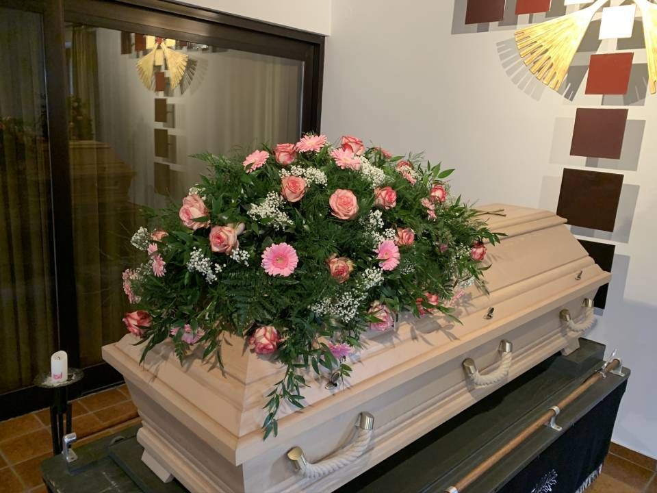 Holzsarg mit Blumenschmuck mit rosafarbenen Gerbera