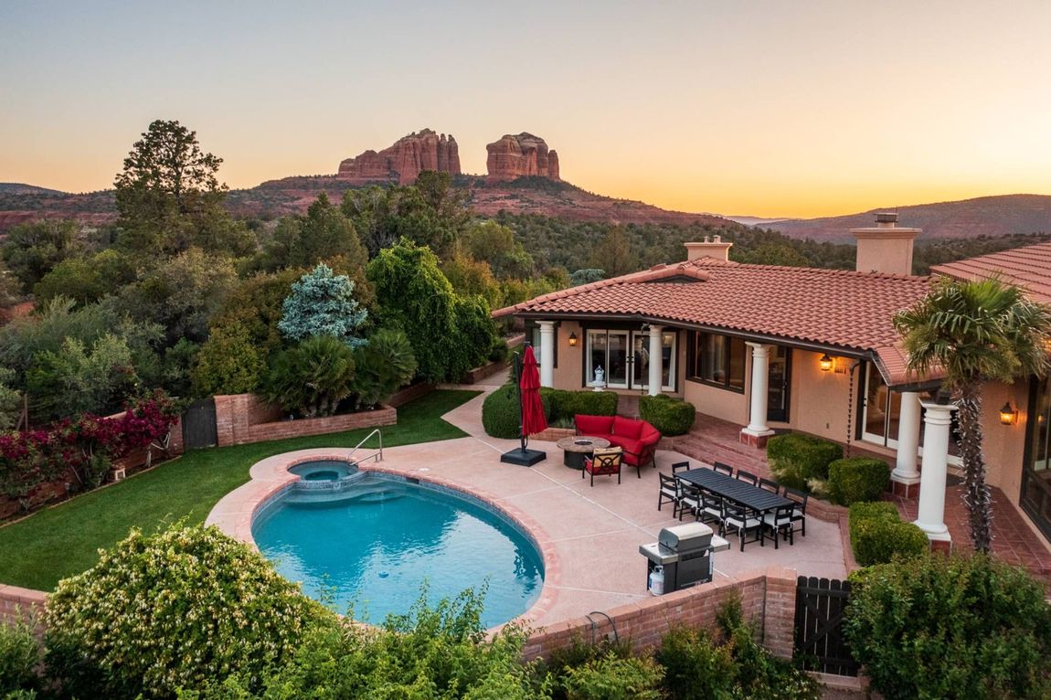Luxurious home with pool overlooking red rock mountains at sunset.