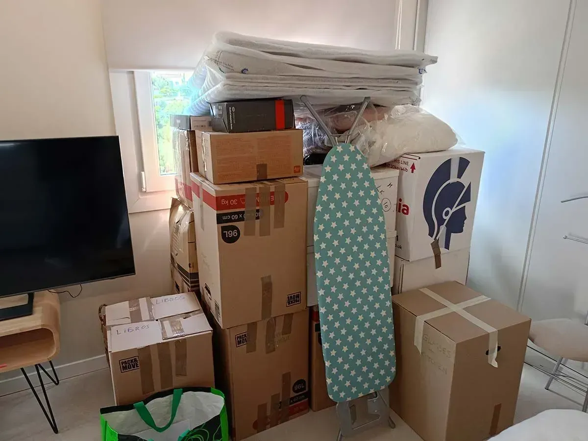 Cajas de mudanza y muebles apilados en una habitación pequeña