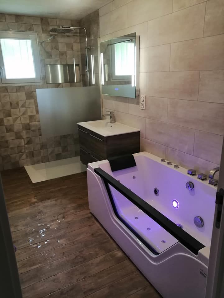 Une salle de bains moderne comprenant une baignoire balnéo blanche avec éclairage intérieur violet.