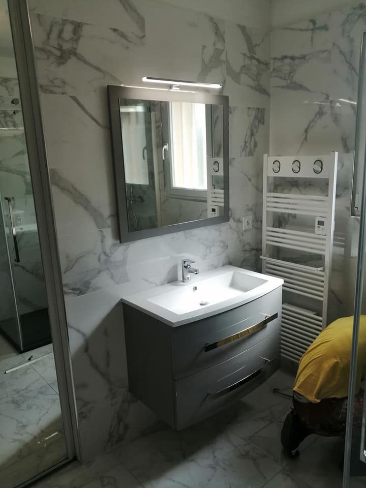 Une salle de bains moderne avec un meuble-lavabo gris, un lavabo blanc et un miroir rétroéclairé.