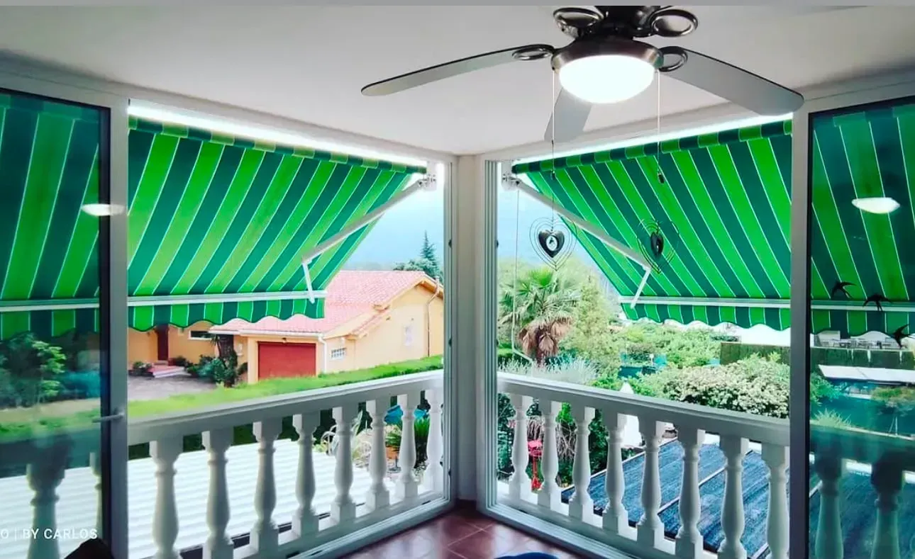 Vista desde el balcón con toldos de rayas verdes, barandilla blanca