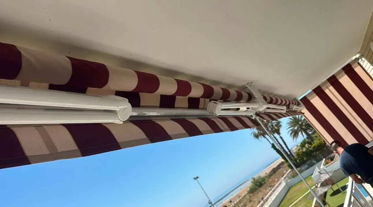 Un toldo de patio a rayas sobre un borde de carretera cubierto de hierba