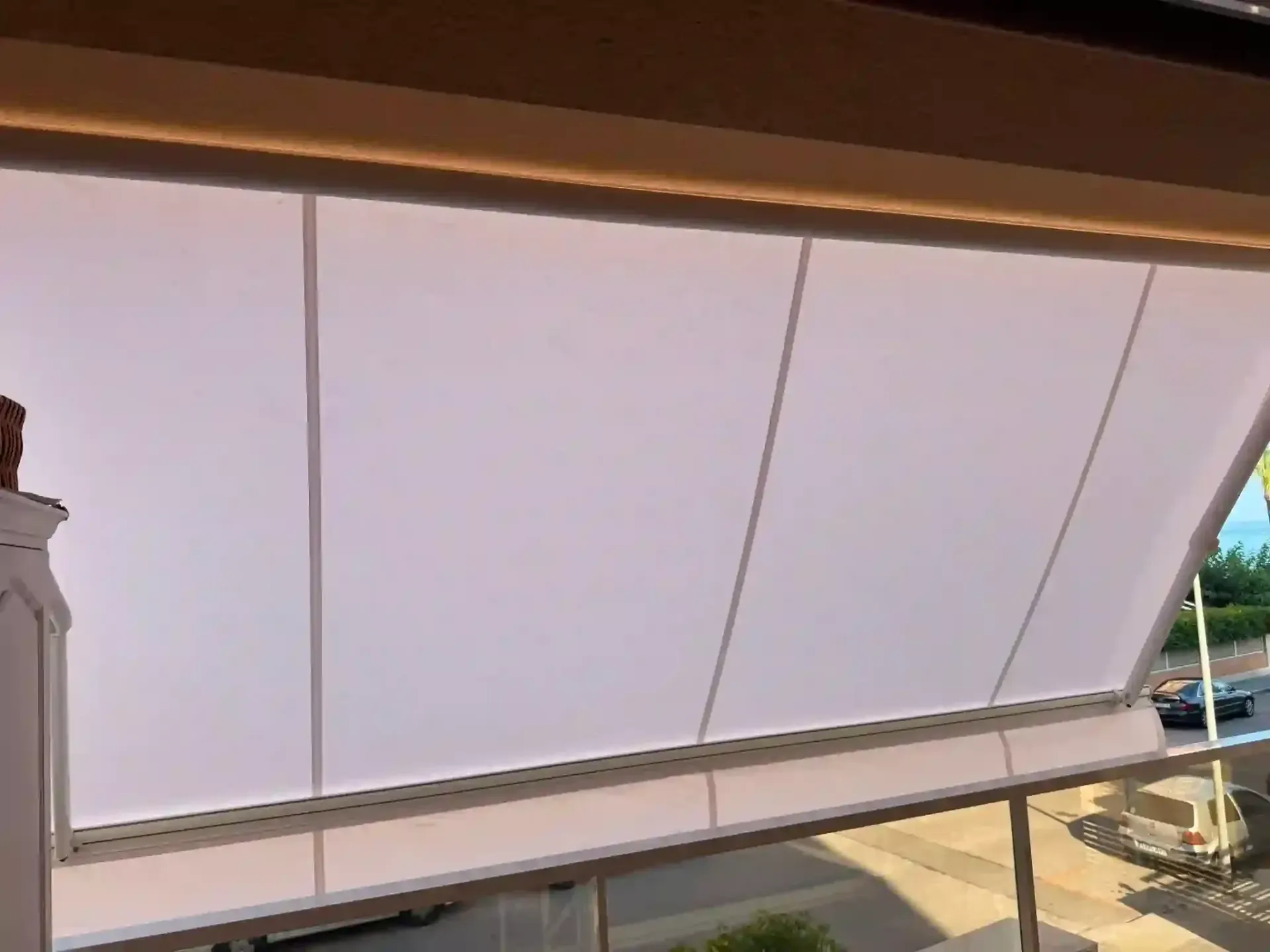 Gran cartel publicitario o panel luminoso blanco bajo un techo marrón, visto desde abajo al aire libre.