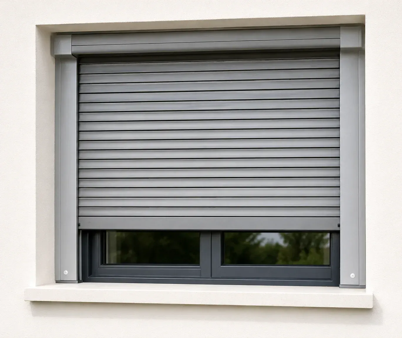 Persiana gris cerrada sobre una pared blanca con una pequeña ventana oscura visible debajo.