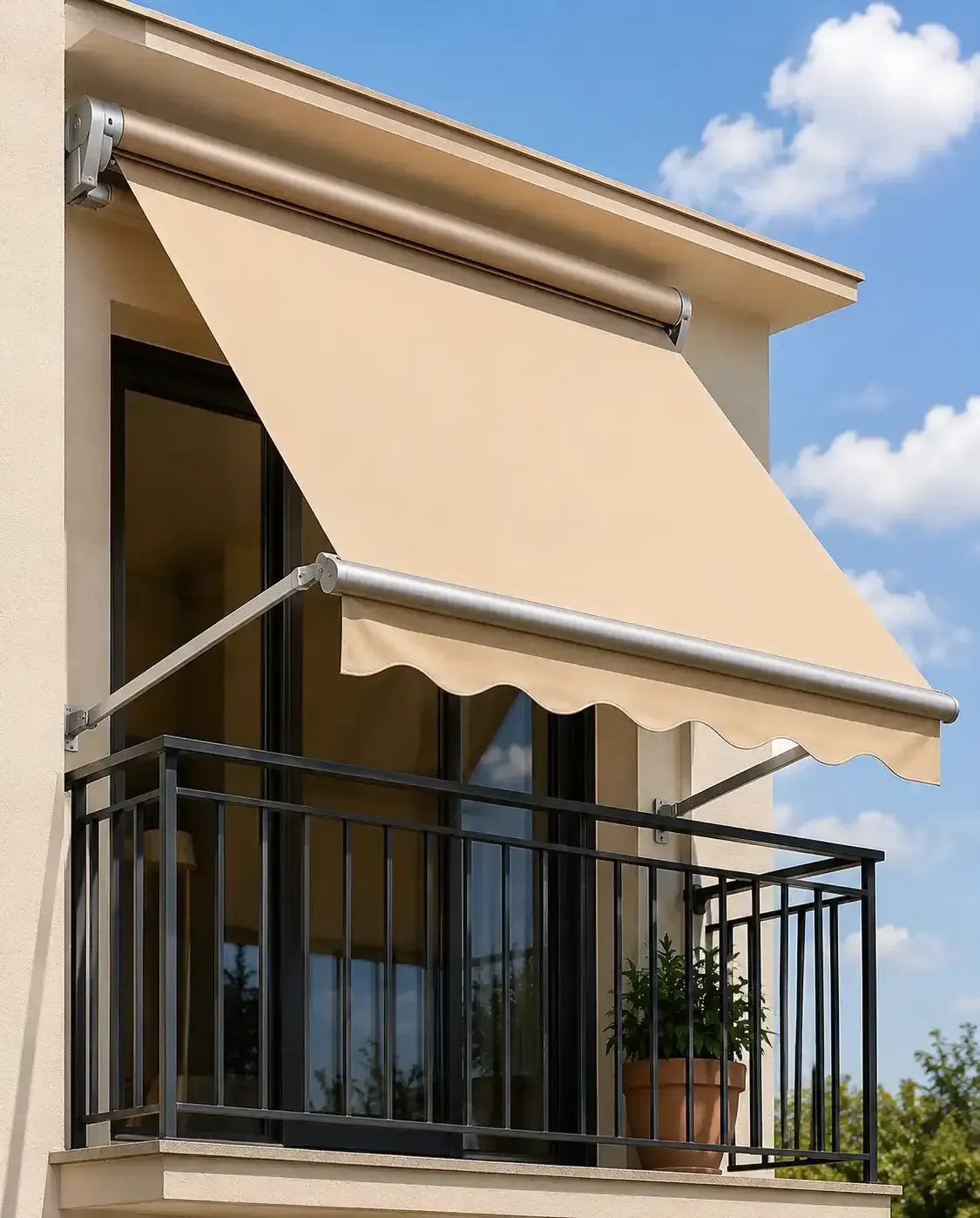 Toldo beige sobre un balcón con barandilla negra y una planta en maceta bajo un cielo azul.