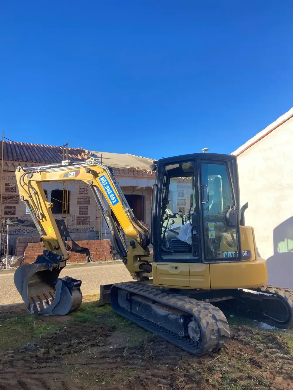 Excavadora amarilla en un sitio de construcción con un cielo azul de fondo.