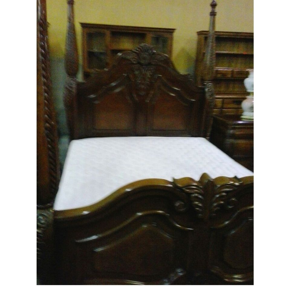 Una cama de madera tallada con un colchón blanco.