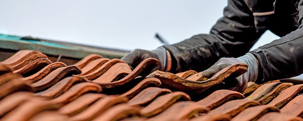 Un ouvrier change les tuiles d'un toit