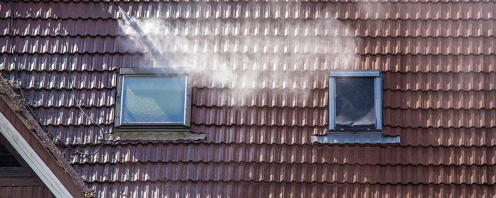 Nettoyage à haute pression de la toiture d'une maison à deux velux