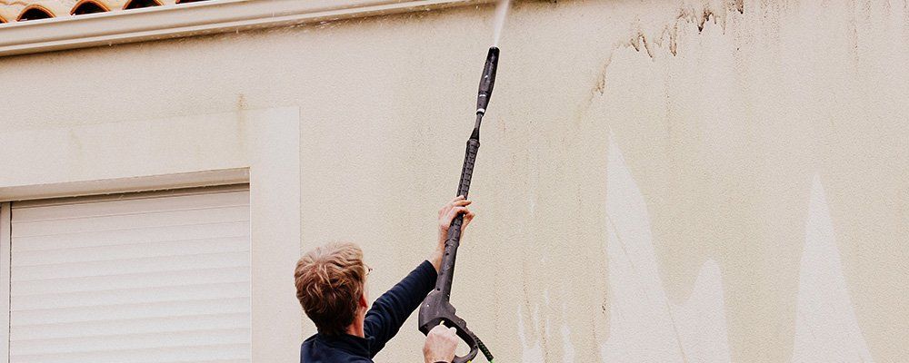 Un homme nettoie le mur avec un nettoyeur à haute pression