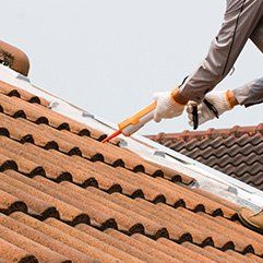 ouvrier appliquant du mastic sur les tuiles