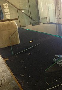 Une table de travail avec des morceaux de verre taillé ; une pièce triangulaire transparente se trouve au premier plan.