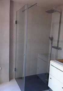 Cabine de douche avec porte en verre et robinetterie argentée dans une salle de bains.