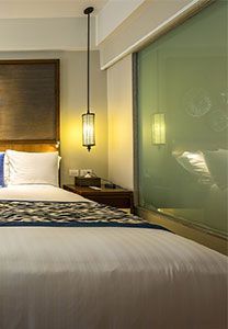 Chambre avec un lit, une table de chevet et une fenêtre. Une lampe suspendue éclaire la scène.