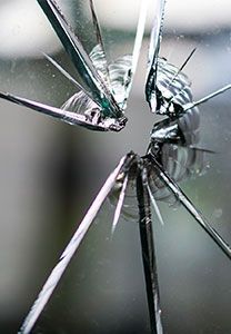 Verre brisé, éclaté autour d'un point d'impact central. Des fragments argentés et transparents rayonnent vers l'extérieur.