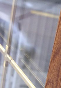 Gros plan sur une fenêtre à grille dorée et encadrement en bois, reflétant un extérieur flou.