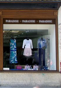 Vitrine d'un magasin de vêtements avec des mannequins portant différentes tenues.