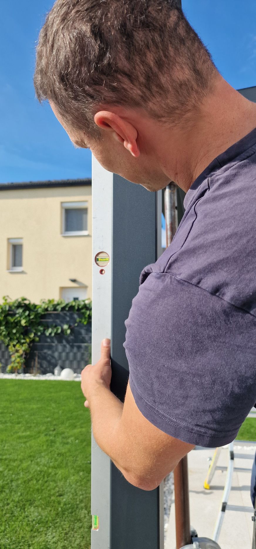 Person, die im Freien eine Holzterrassendiele mit einer Bohrmaschine festschraubt.