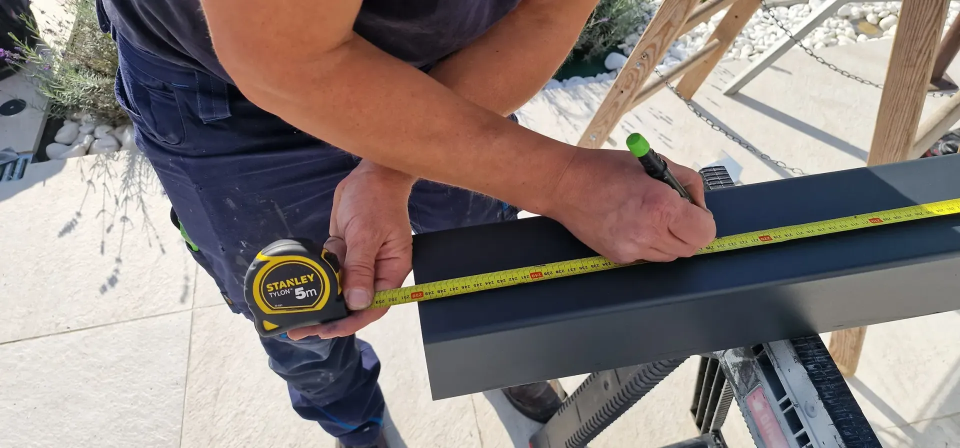 Mann im Overall bohrt mit einer Bohrmaschine an einem Fensterrahmen.