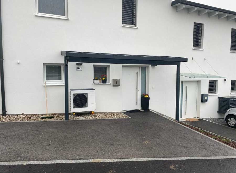 White townhouse with black awning over door, asphalt driveway.
