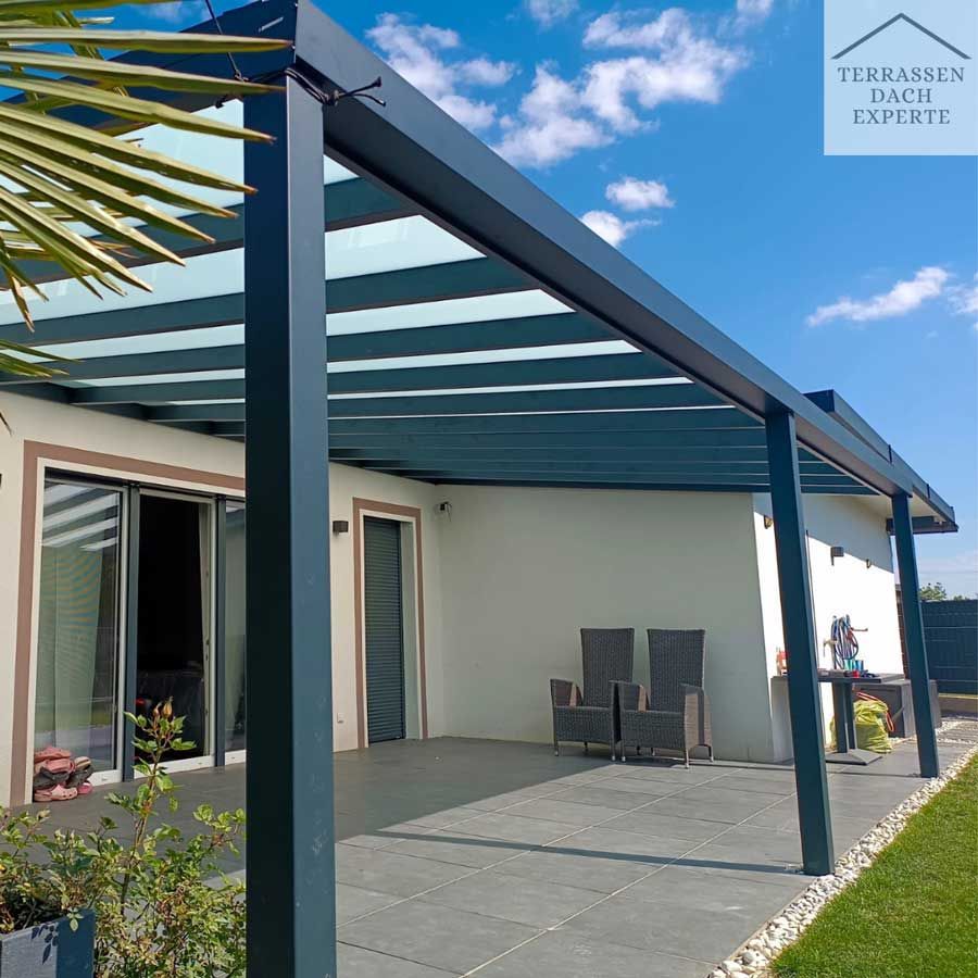 Blue-grey patio roof over a porch with chairs, near a house with a clear blue sky.