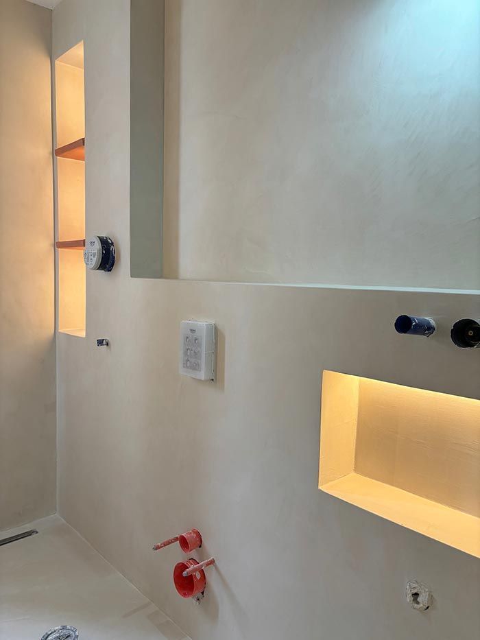 Un baño con inodoro, lavabo, espejo y estantes.