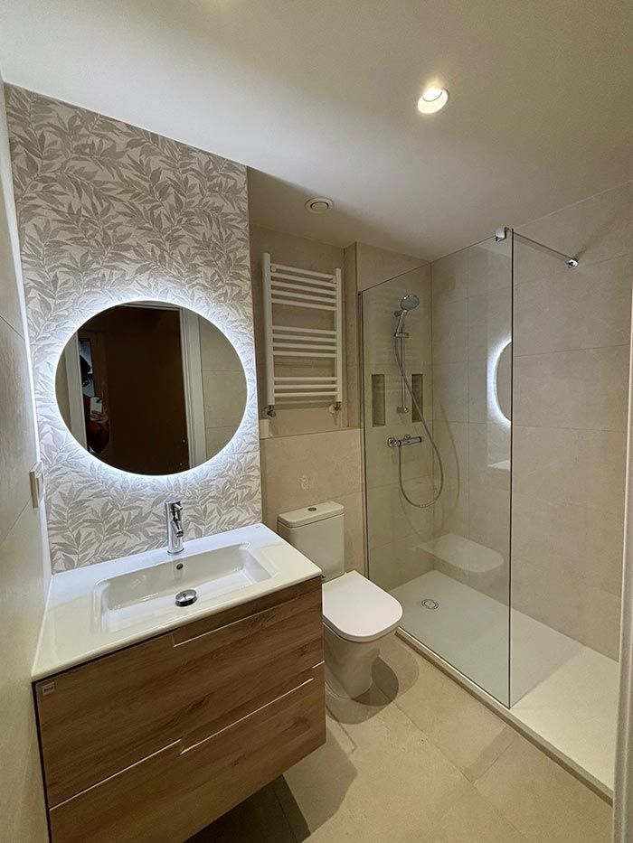 Un baño con lavabo, inodoro, ducha y espejo.