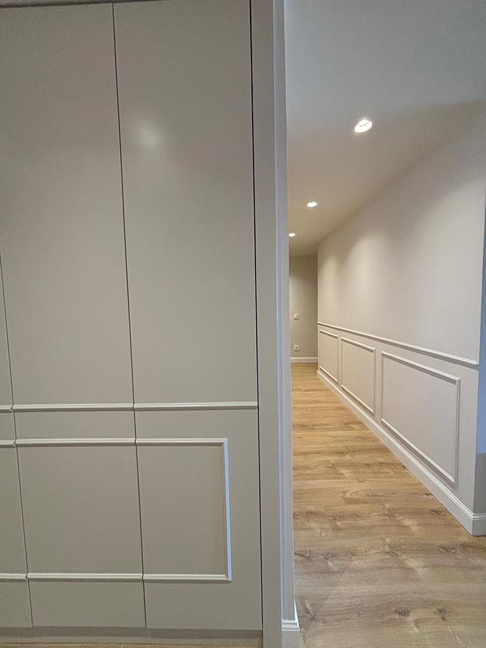 Un largo pasillo con paredes blancas y pisos de madera en una casa.