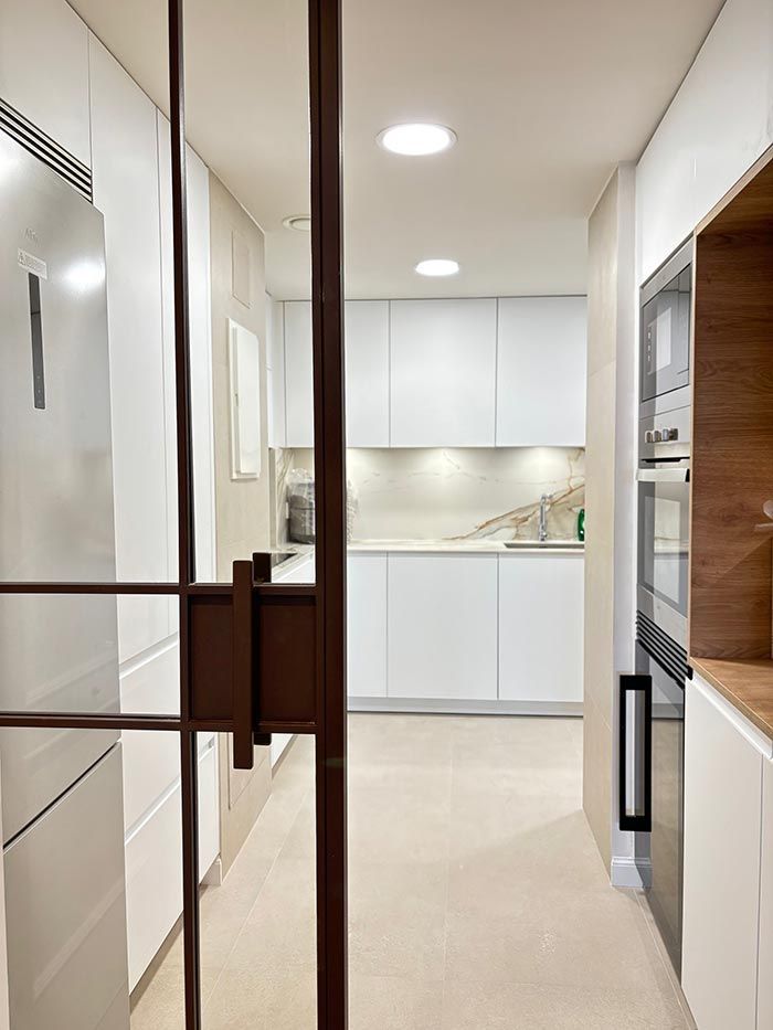 Una cocina con gabinetes blancos, electrodomésticos de acero inoxidable y una puerta de vidrio.