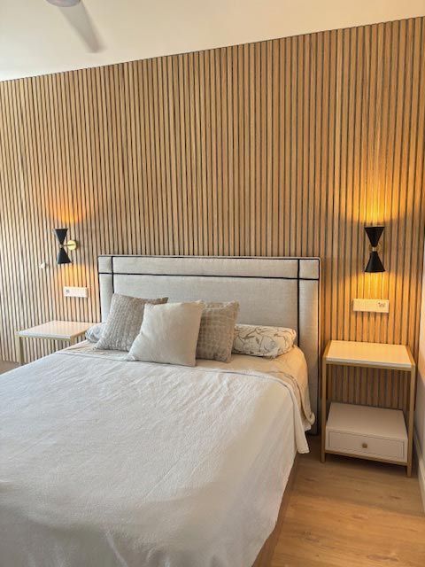Un dormitorio con una cama, dos mesitas de noche y una pared de madera.