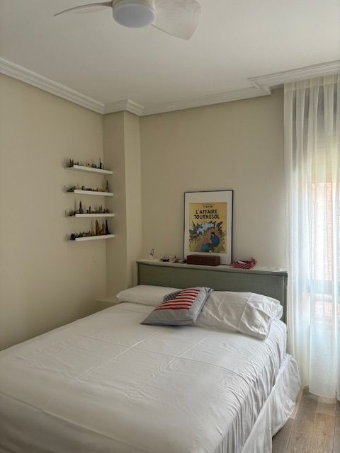 Un dormitorio con una cama y un ventilador de techo.