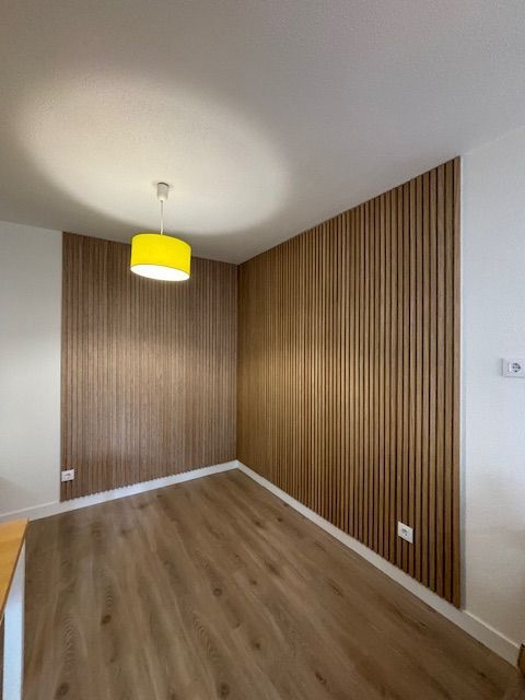 Una habitación con paredes de madera y una lámpara amarilla colgando del techo.