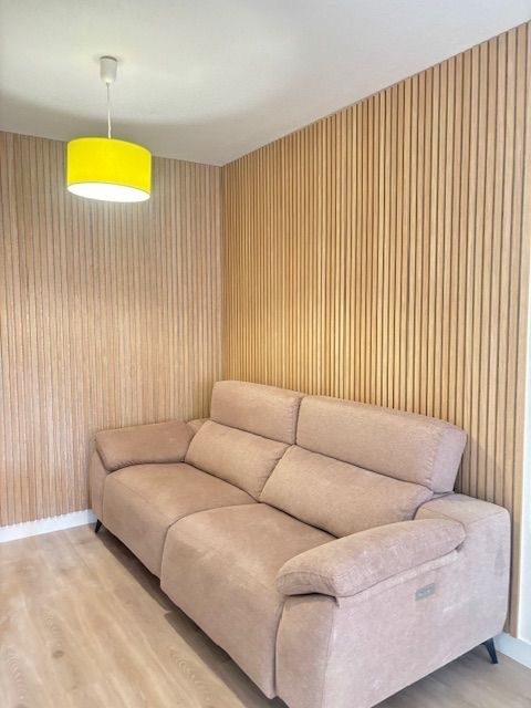 Una sala de estar con un sofá y una lámpara amarilla colgando del techo.