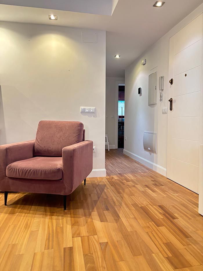 Una silla rosa está en un pasillo al lado de una puerta.