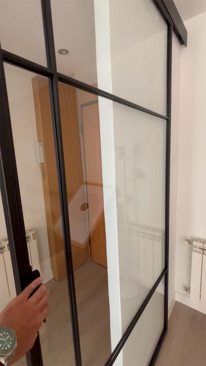 Una persona sostiene un teléfono celular frente a una puerta de vidrio.