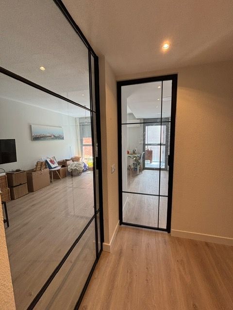 Un pasillo con una puerta de cristal que conduce a una sala de estar.