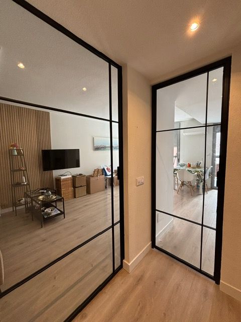 Un pasillo con el reflejo de una sala de estar en el espejo.