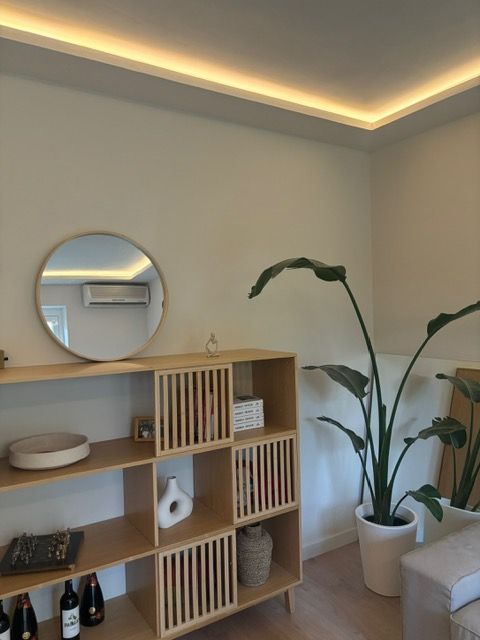 Una sala de estar con una planta y un espejo redondo.