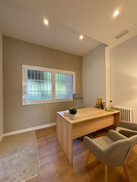 Una habitación con un escritorio y sillas y una ventana.