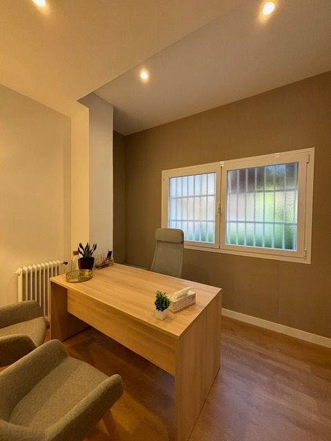 Una habitación con un escritorio y sillas y una ventana.