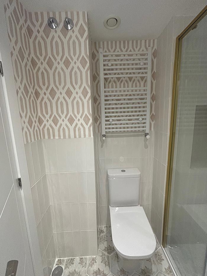 Un baño con inodoro, ducha y toallero.