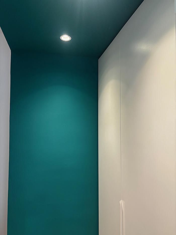Un baño con paredes de color verde azulado y techo blanco.