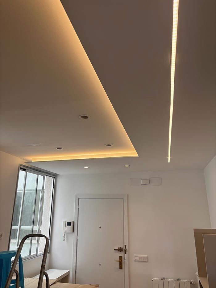 Una sala de estar con una escalera y una luz en el techo.