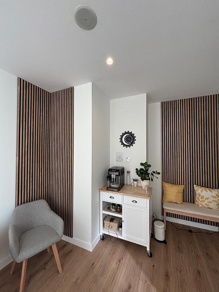 Una sala de estar con pisos de madera, una silla, una cafetera y un banco.