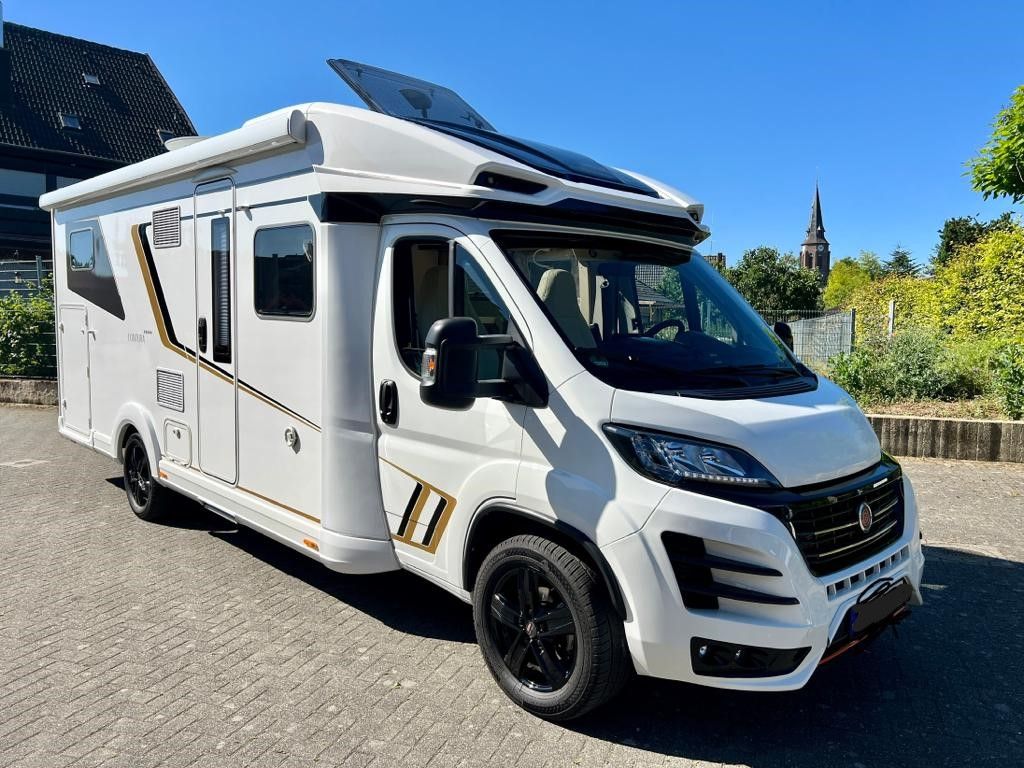 Ein weißes Wohnmobil steht auf einem Parkplatz.