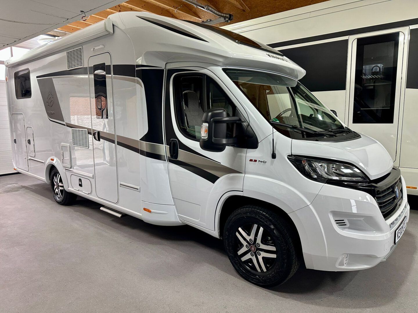 Ein weißes Wohnmobil steht in einem Ausstellungsraum.